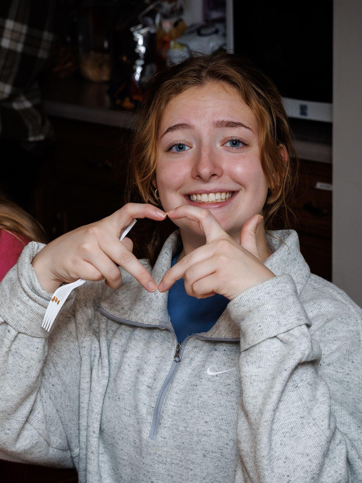 A student makes a heart sign with her hands at a retreat breakfast