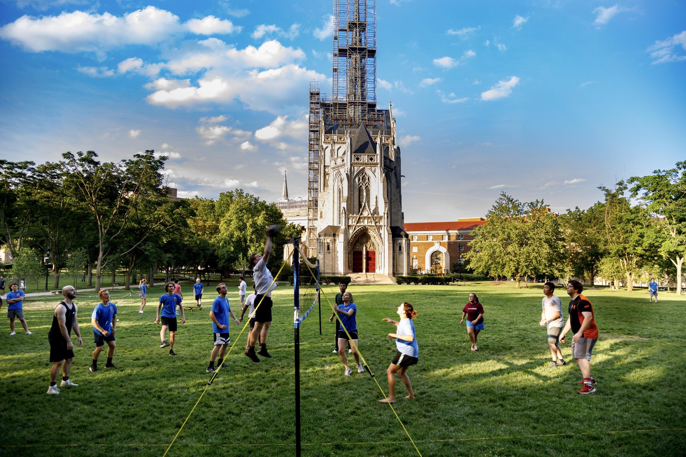Students play volleyball on the university lawn in golden evening light
